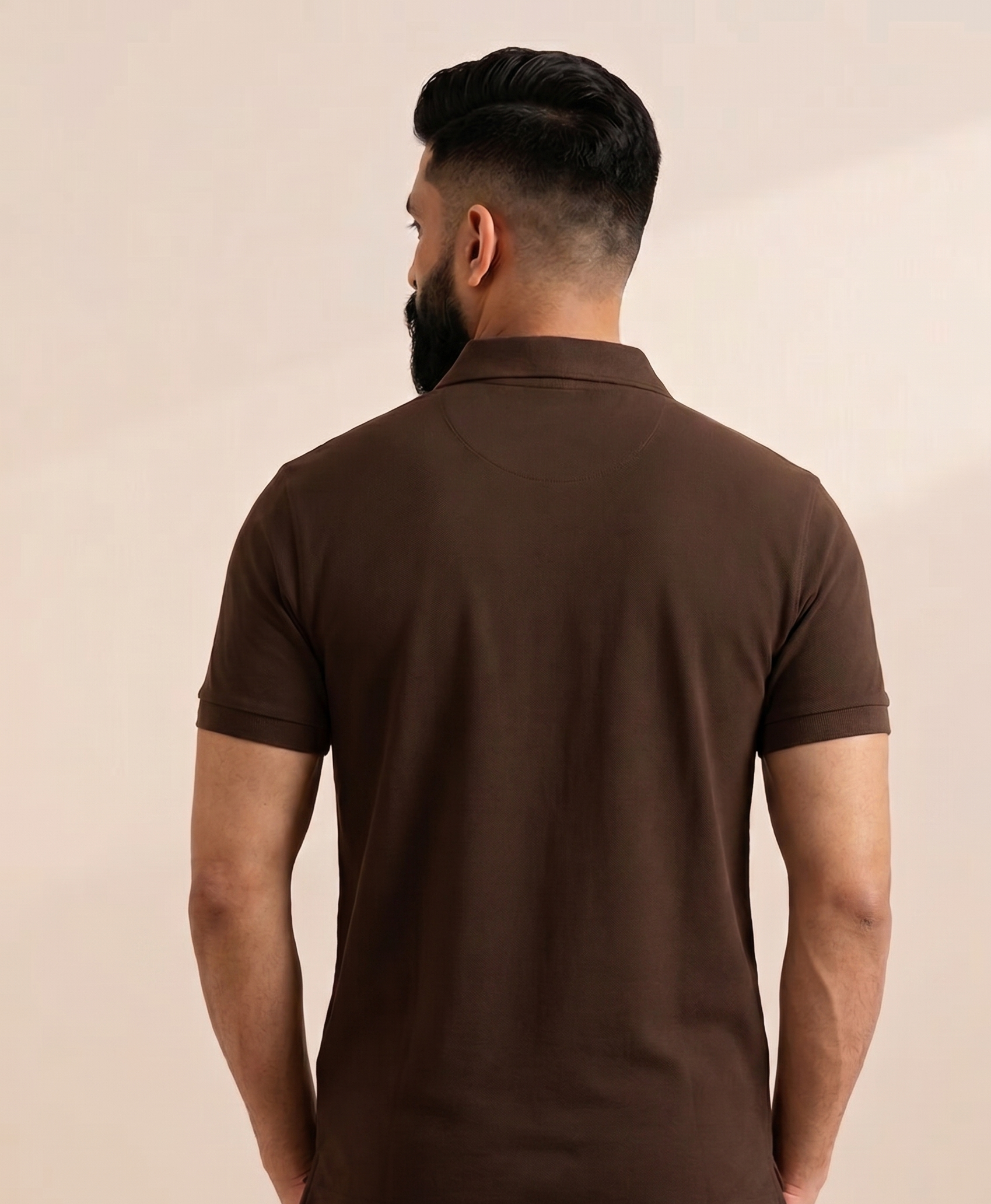 Man wearing a brown polo shirt against a beige background